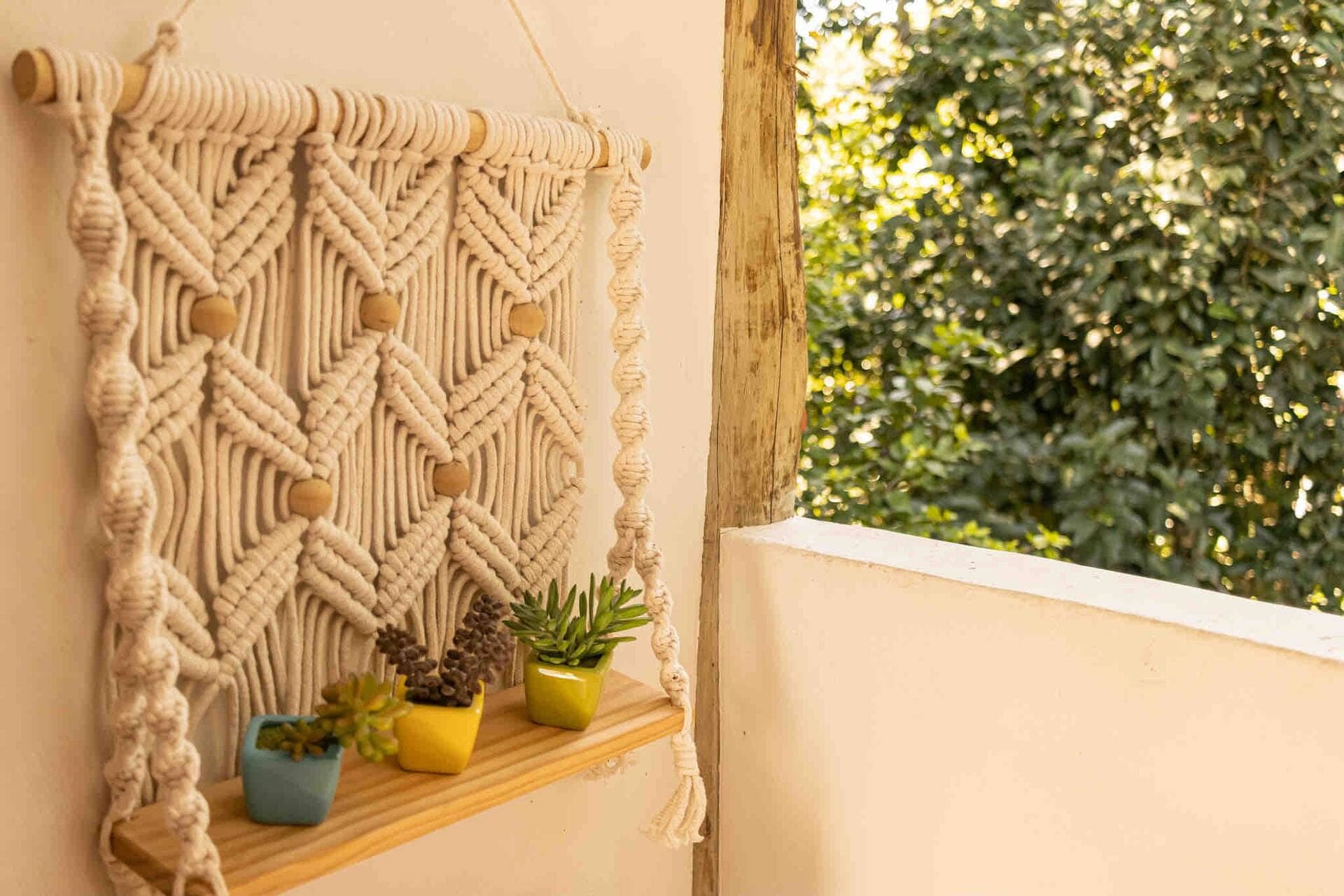 Painel de macramê com prateleira de suculentas junto à varanda
