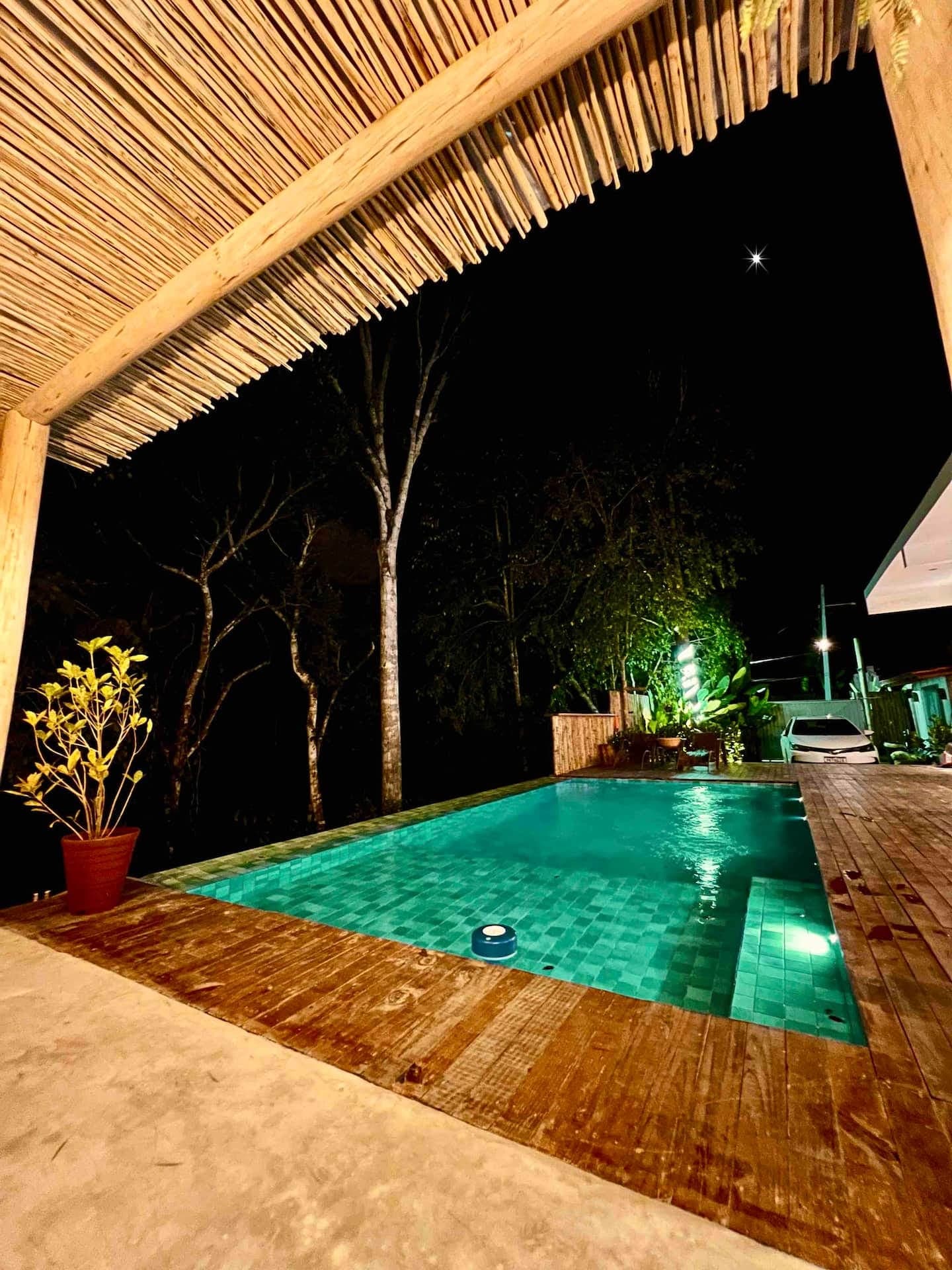 Piscina iluminada à noite sob o telhado de bambu